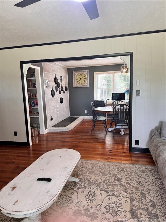 living room with dark wood-type flooring and crown molding