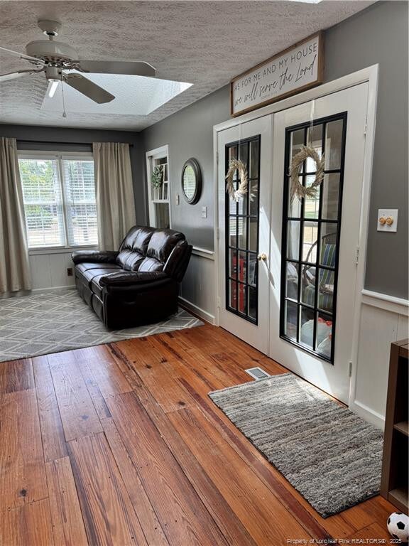 unfurnished living room featuring french doors, ceiling fan, a textured ceiling, and hardwood / wood-style flooring