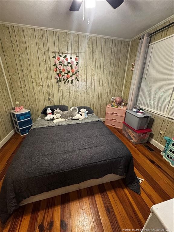 bedroom with crown molding, wood-type flooring, and ceiling fan