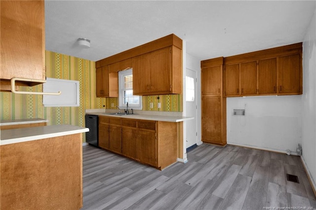 kitchen featuring dishwasher, kitchen peninsula, sink, and light hardwood / wood-style flooring