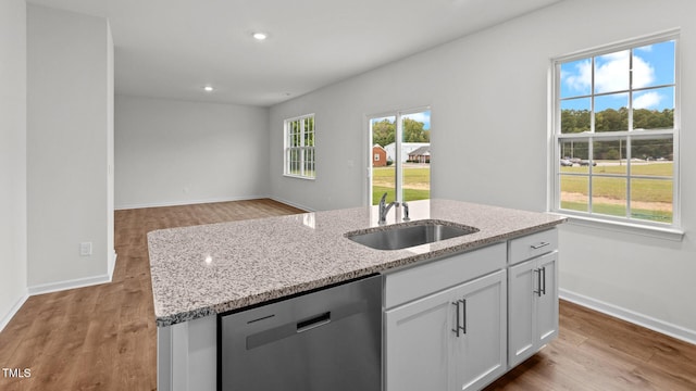 kitchen with sink, white cabinetry, light stone counters, dishwasher, and a kitchen island with sink