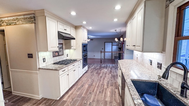 kitchen featuring sink, hanging light fixtures, wall oven, light stone countertops, and dark wood-type flooring