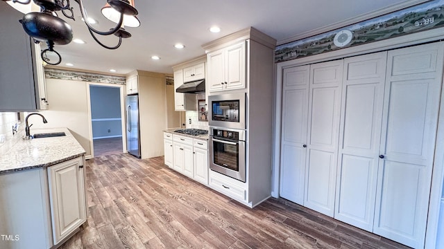 kitchen with appliances with stainless steel finishes, dark hardwood / wood-style floors, white cabinetry, sink, and light stone countertops