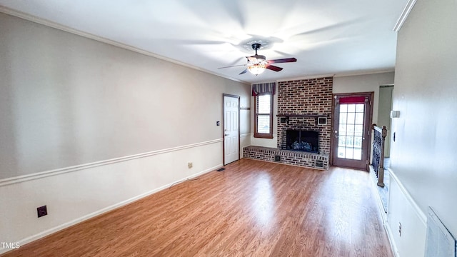 unfurnished living room with ceiling fan, crown molding, a fireplace, and wood-type flooring