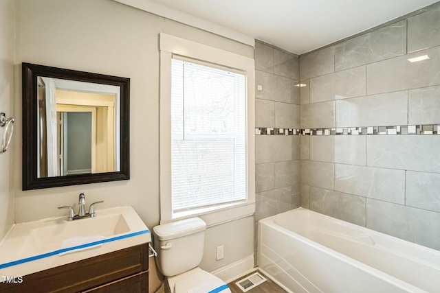 full bathroom with vanity, tiled shower / bath combo, a wealth of natural light, and toilet