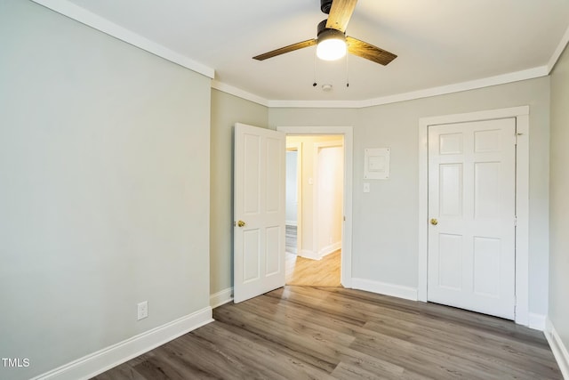 unfurnished bedroom featuring crown molding, wood-type flooring, and ceiling fan