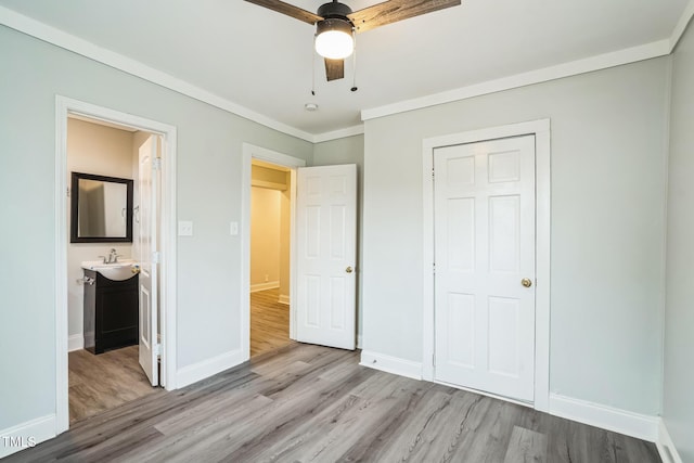 unfurnished bedroom with ensuite bathroom, sink, ornamental molding, ceiling fan, and light wood-type flooring