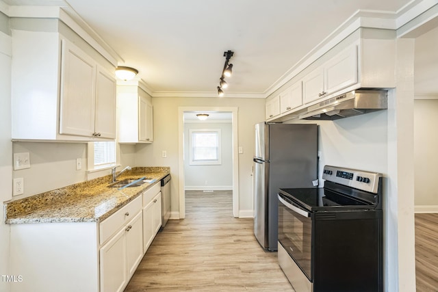 kitchen with appliances with stainless steel finishes, sink, white cabinets, light stone countertops, and light hardwood / wood-style flooring