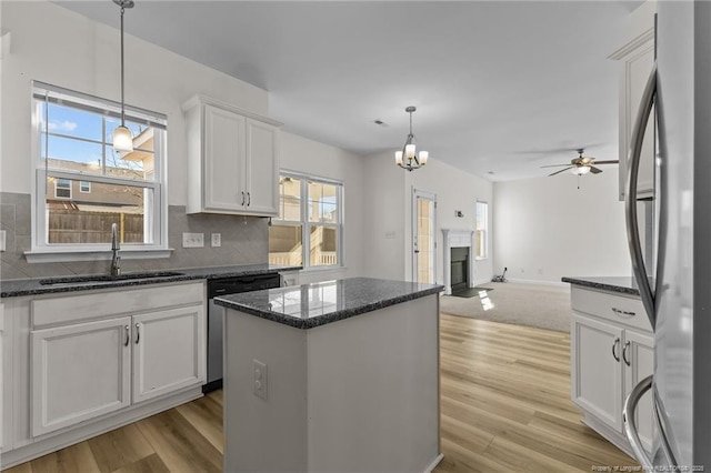 kitchen featuring sink, decorative light fixtures, a center island, stainless steel appliances, and white cabinets