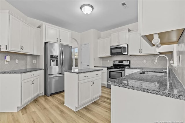 kitchen featuring sink, light hardwood / wood-style flooring, appliances with stainless steel finishes, white cabinetry, and a center island