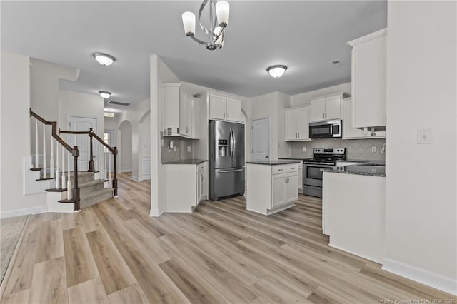 kitchen with white cabinetry, appliances with stainless steel finishes, hanging light fixtures, and backsplash