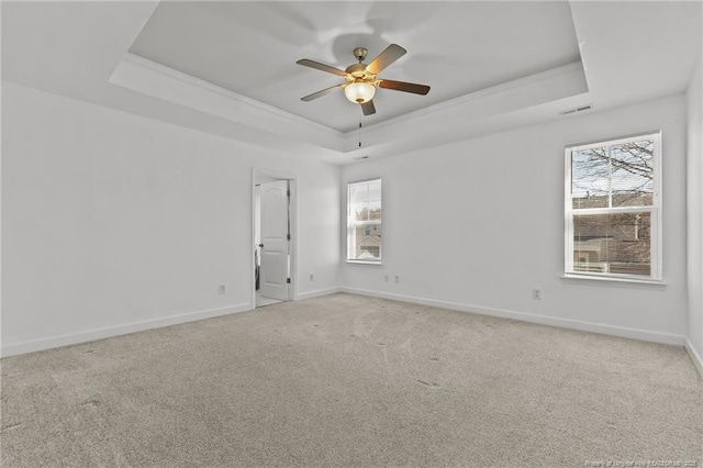 carpeted spare room featuring a raised ceiling and ceiling fan