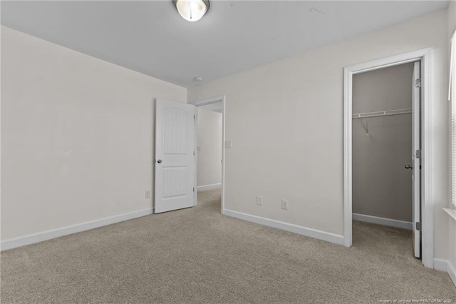 unfurnished bedroom with light carpet, a walk in closet, and a closet