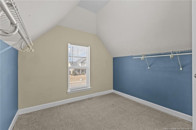 walk in closet with vaulted ceiling and light colored carpet