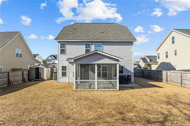 rear view of property with a storage unit, a yard, and a sunroom