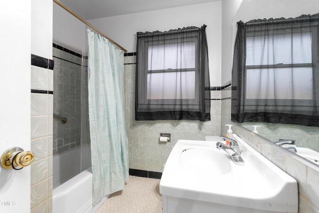 bathroom with shower / bath combo with shower curtain, sink, and tile walls