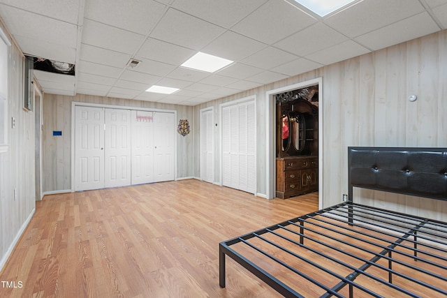 unfurnished bedroom featuring wood-type flooring, wooden walls, and a paneled ceiling