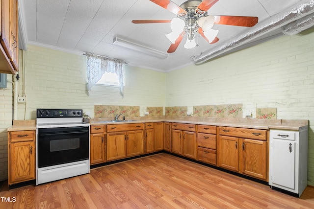 kitchen with brick wall, electric range oven, sink, and light hardwood / wood-style flooring