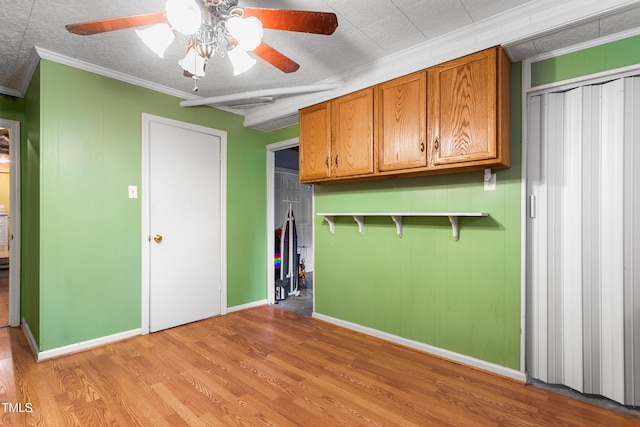 kitchen featuring a textured ceiling, ornamental molding, ceiling fan, and light wood-type flooring