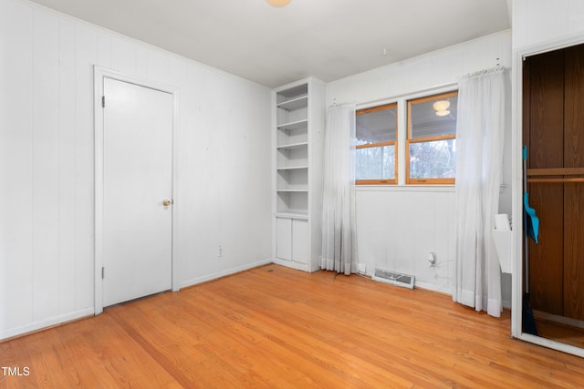 unfurnished bedroom featuring crown molding and light hardwood / wood-style floors