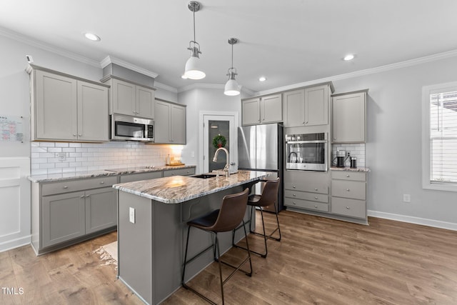 kitchen featuring stainless steel appliances, gray cabinets, and light stone countertops