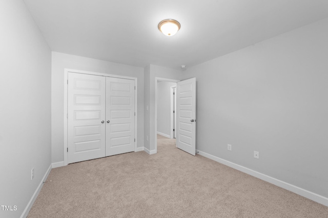 unfurnished bedroom featuring light carpet and a closet