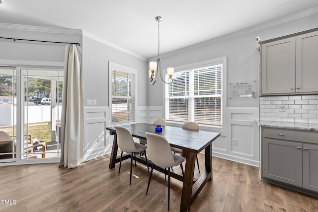 dining space with hardwood / wood-style flooring, plenty of natural light, ornamental molding, and a chandelier