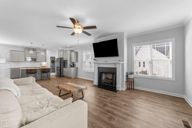 living room with crown molding, wood-type flooring, and ceiling fan