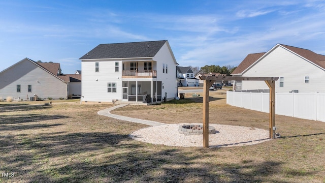 back of house with a fire pit, a pergola, a yard, a sunroom, and a balcony