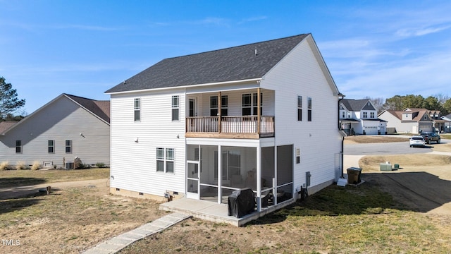 rear view of property featuring a balcony, a sunroom, and a yard