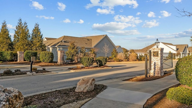 65 Balsam Ln, Clayton, NC 27527 - view of asphalt road with a gate, sidewalks, street lights, and curbs