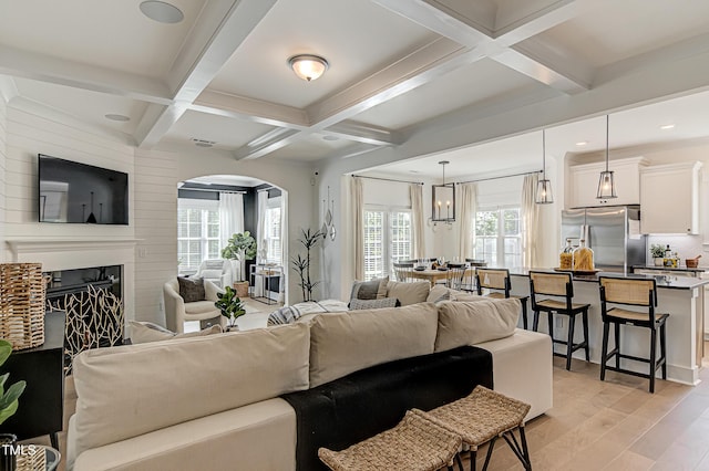 living room with coffered ceiling, light hardwood / wood-style floors, and beam ceiling