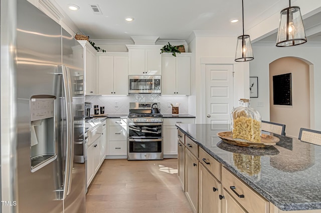 kitchen featuring appliances with stainless steel finishes, dark stone counters, a kitchen island, and white cabinets