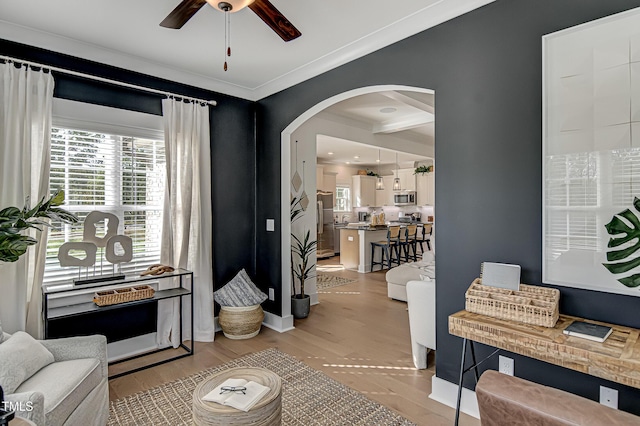 living room featuring ornamental molding, light hardwood / wood-style floors, and ceiling fan