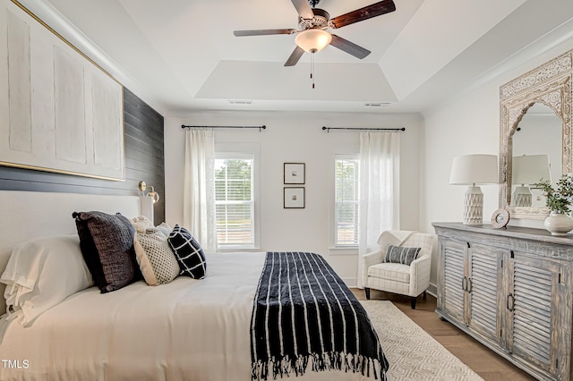 bedroom with hardwood / wood-style floors, a raised ceiling, and ceiling fan