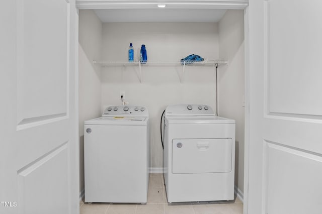 clothes washing area with laundry area, washer and clothes dryer, and light tile patterned flooring