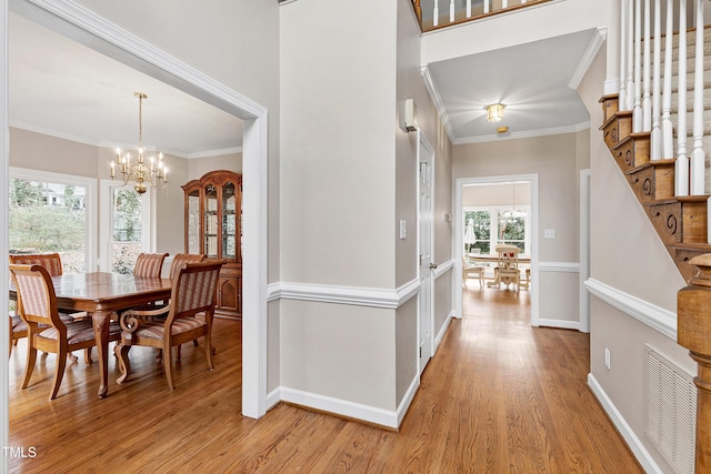 dining area with ornamental molding, a notable chandelier, and light hardwood / wood-style floors