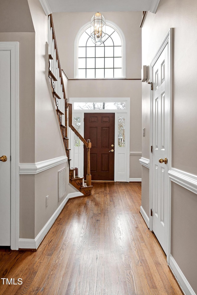 foyer featuring a notable chandelier, light hardwood / wood-style floors, and a high ceiling