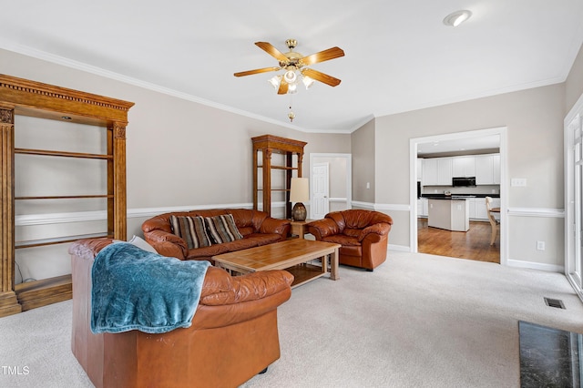 carpeted living room with crown molding and ceiling fan