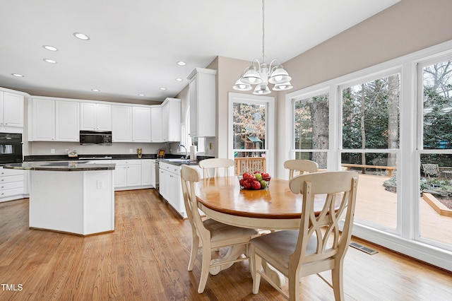 dining space with a notable chandelier, sink, and light wood-type flooring