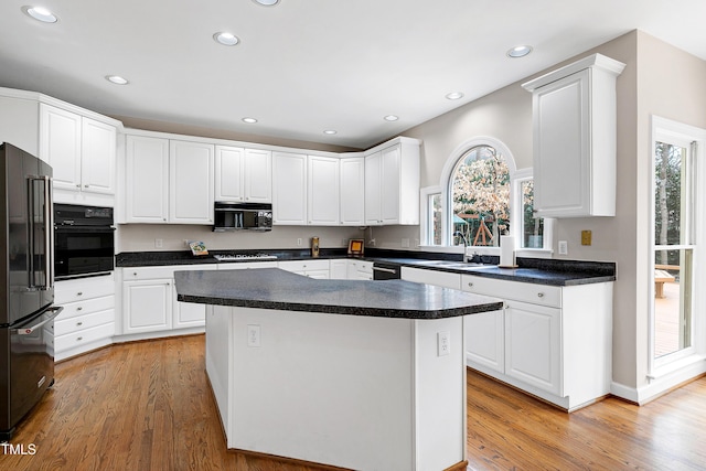 kitchen with white cabinetry, a center island, a healthy amount of sunlight, and black appliances