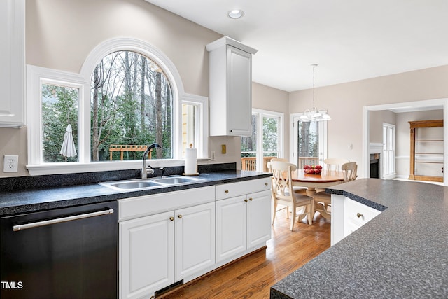 kitchen featuring dishwasher, sink, white cabinets, and decorative light fixtures