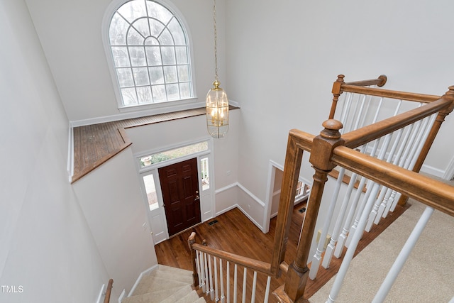 entryway with a high ceiling, wood-type flooring, and a notable chandelier