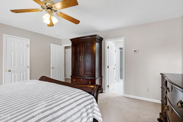 bedroom featuring light colored carpet, ceiling fan, and ensuite bath