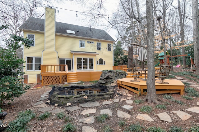 back of house with a wooden deck and a playground