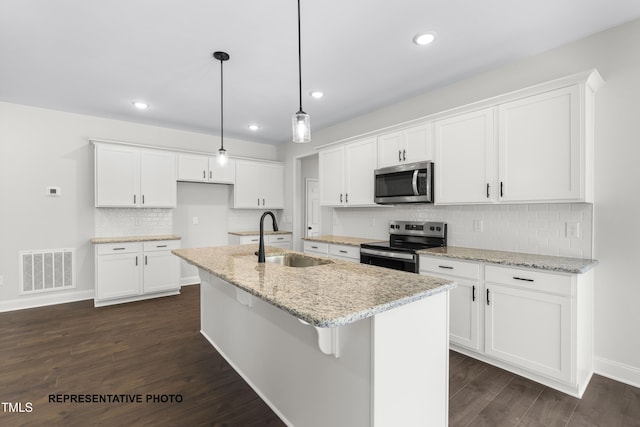 kitchen with dark wood-style floors, a center island with sink, visible vents, a sink, and stainless steel appliances