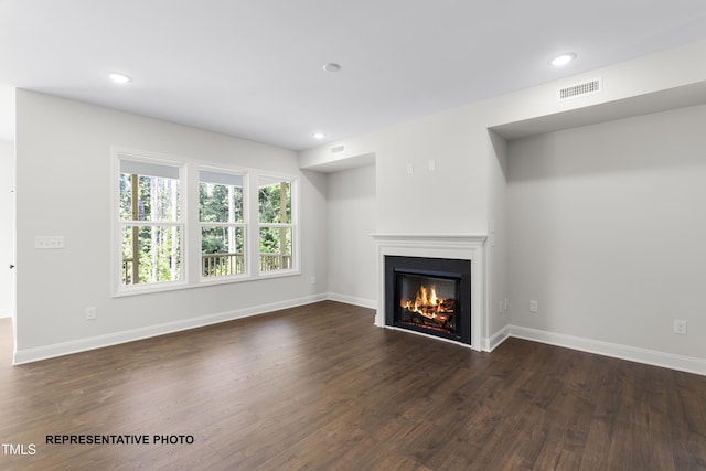 unfurnished living room featuring visible vents, baseboards, dark wood finished floors, recessed lighting, and a glass covered fireplace