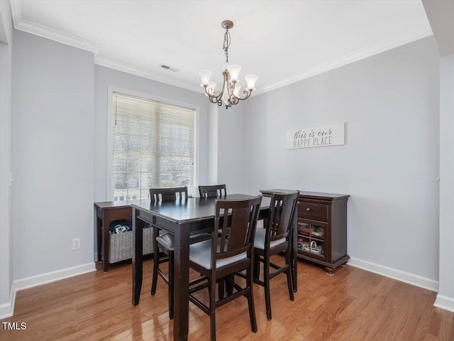 dining space featuring crown molding, a chandelier, and light wood-type flooring