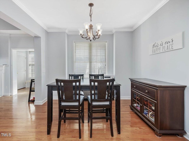 dining room with an inviting chandelier, ornamental molding, and light wood-type flooring