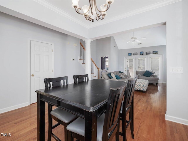 dining area featuring lofted ceiling, crown molding, hardwood / wood-style floors, decorative columns, and ceiling fan with notable chandelier